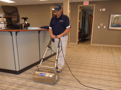 A Duo Care worker using an encapsulating system to clean carpet in an office