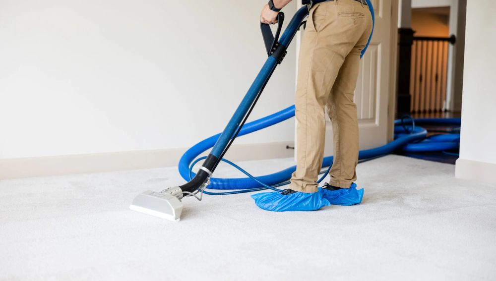 A person wearing booties steam cleans white carpet
